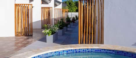 A swimming pool with a tiled edge, surrounded by white walls and wooden fences.