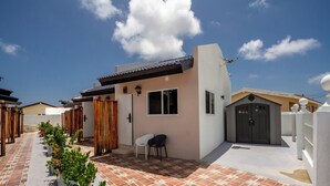 A residential building with a tiled patio, a small seating area, and a garage. - Aruba Vibe Apartments #2 | A charming place near the beaches and the city center (Oranjestad)