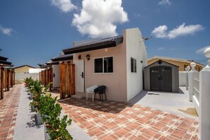 A residential building with a tiled patio, a small seating area, and a garage. - Aruba Vibe Apartments #2 | A charming place near the beaches and the city center (Oranjestad)