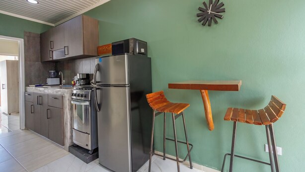 A kitchen with a refrigerator, stove, microwave, and a clock on the wall. - Aruba Vibe Apartments #2 | A charming place near the beaches and the city center (Oranjestad)