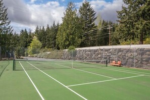 A tennis court with a stone wall and trees in the background. - WM BLOCK Discovery Bay 2br (Port Townsend)