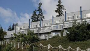 Ein mehrgeschossiges Gebäude mit Balkonen, umgeben von Bäumen und einer Steinmauer.