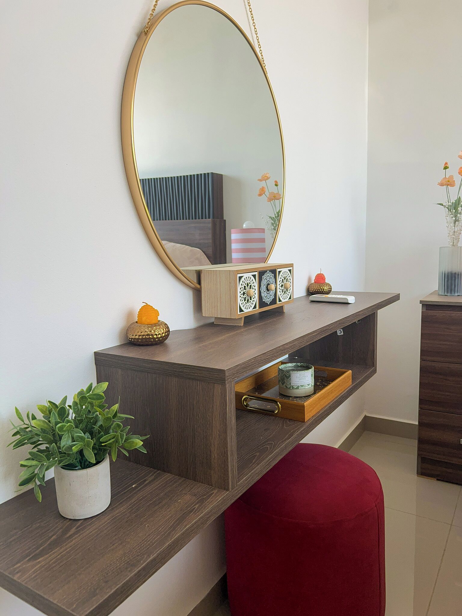 A modern bathroom with a wooden vanity, a large mirror, and a red stool.