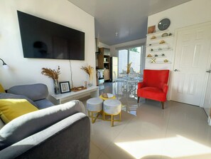 A modern living room with a sofa, armchairs, a red chair, and a dining area with a table and chairs. - Home in San Miguel (San Miguel)