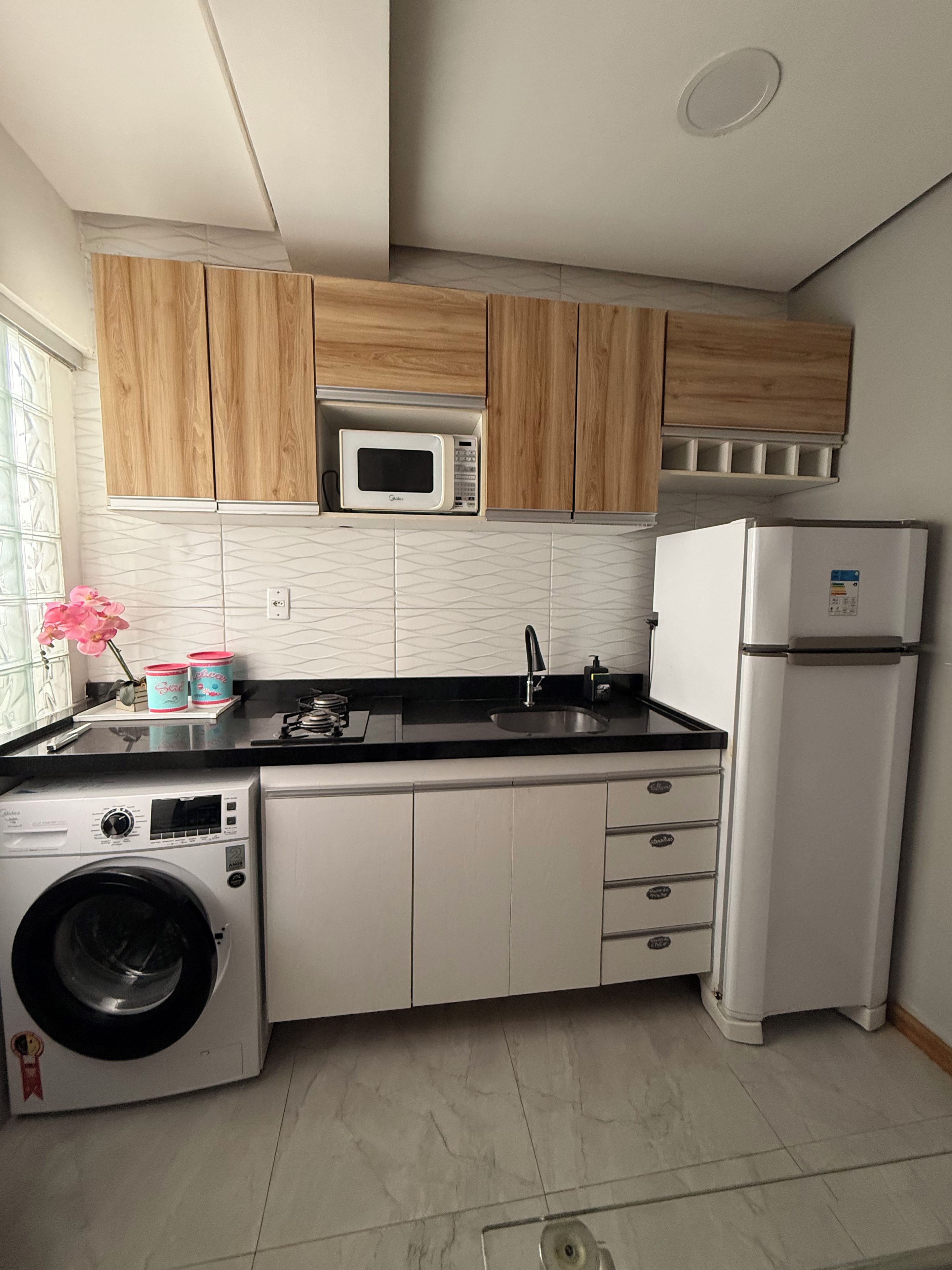 Cocina compacta equipada con microondas, refrigerador, lavadora y lavaplatos.