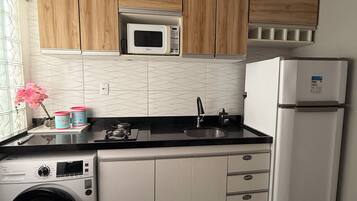 Cocina compacta equipada con microondas, refrigerador, lavadora y lavaplatos.