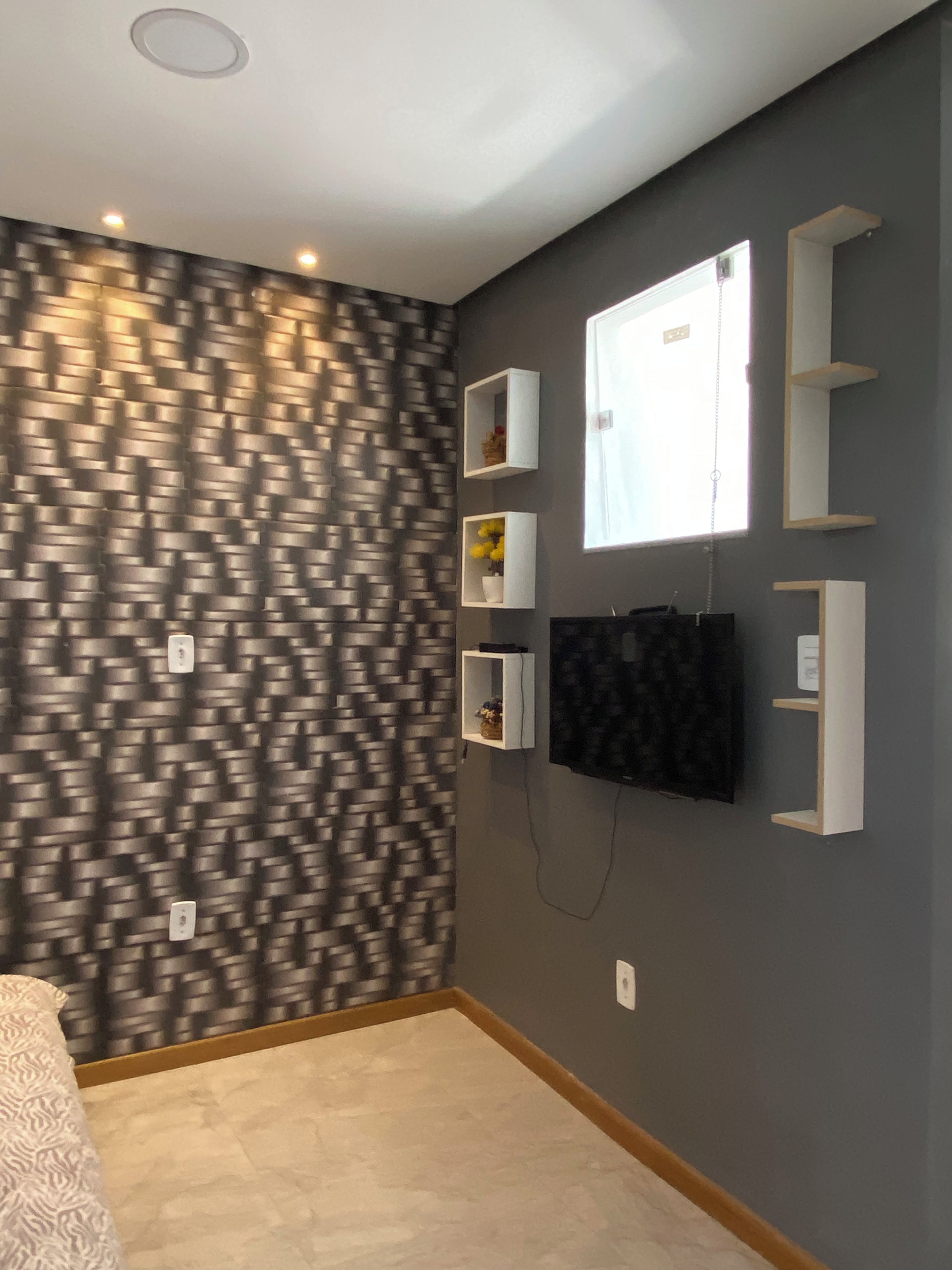 Una habitación con pared estampada, estantes empotrados, un televisor de pantalla plana y una ventana.