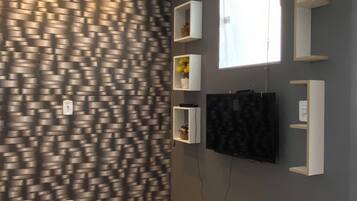 Una habitación con pared estampada, estantes empotrados, un televisor de pantalla plana y una ventana.