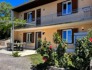 Ein zweistöckiges Gebäude mit Balkon, Außenbereich und einem Blumengarten.