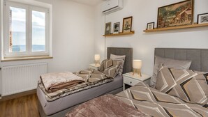 Ein Schlafzimmer mit zwei Betten, einem Fenster, einer Klimaanlage und einem Bild an der Wand.
