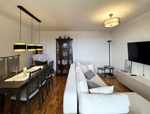Ein modernes Wohnzimmer mit Essbereich, einer Sofagarnitur, einem Schrank und einem Flachbildfernseher.