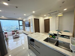 A modern kitchen with a marble countertop, built-in appliances, and a large window offering a city view. - Designer Corner 2BR with Wide Saigon Views and AC (Thành phố Hồ Chí Minh)