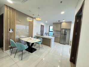 A modern kitchen with a marble countertop, stainless steel appliances, and a dining area with a marble table and teal chairs. - Designer Corner 2BR with Wide Saigon Views and AC (Thành phố Hồ Chí Minh)