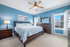 A bedroom with a bed, nightstands, a dresser, a ceiling fan, and a window with curtains. - "Pipe Dreams" -- 50 Steps To Beach, Gulf View, Dog Friendly, Super Cute 3BR Home (Gulf Shores)