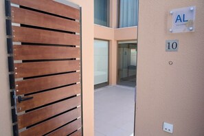 A modern building entrance with a wooden gate, a glass door, and a wall with a sign reading 'AL' and the number '10'. - Villa Salgados private pool (Guia)