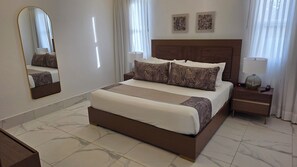 A hotel room with a large bed, a nightstand, a mirror, and two wall-mounted artworks. - Sophisticated 3 to 7 bedroom Royal Villas @ Lifestyle Holidays, Puerto Plata, DR (Cofresi)