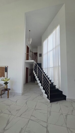 A spacious interior with a marble-tiled floor, a staircase with a metal railing, and a large window with sheer curtains. - Sophisticated 3 to 7 bedroom Royal Villas @ Lifestyle Holidays, Puerto Plata, DR (Cofresi)