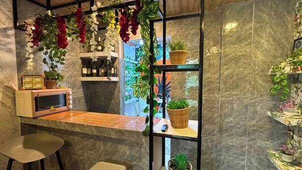 A bar area with a wooden ceiling, a marble countertop, and shelves with potted plants.