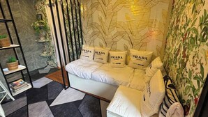 A modern room with a sofa adorned with Prada pillows, a patterned wall, and a geometric floor design.