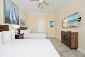 A hotel room with two beds, a ceiling fan, a TV, and artwork on the walls. - Phoenix Orange Beach 1202 (Orange Beach)
