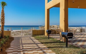 A patio area with a view of the beach, outdoor seating, and a grill. - Phoenix Orange Beach 1202 (Orange Beach)