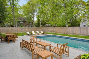 Ein Garten mit Swimmingpool, Holzterrasse und Liegestühlen.