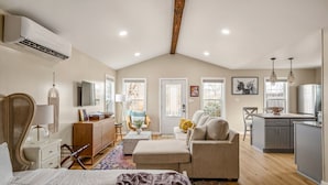 A spacious loft with a high ceiling, a dining area, a kitchen, and a living room with a large window. - Janis, Cozy 1-Bedroom Retreat in Gladheart, Sleeps 4, Hot Tub & Fire Pit (Fredericksburg)