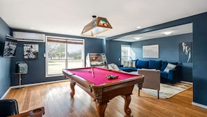 A pool room with a pool table, a sofa, and a large window. - Janis, Cozy 1-Bedroom Retreat in Gladheart, Sleeps 4, Hot Tub & Fire Pit (Fredericksburg)