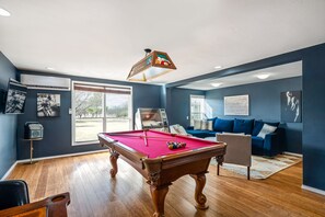 Ein Poolraum mit Pooltisch, einer Sitzecke und einem großen Fenster.