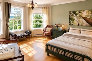 A bedroom with a large bed, a nightstand, a chair, and a window with curtains.
