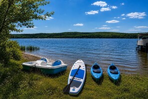 A lakeside view with boats and a paddleboard.