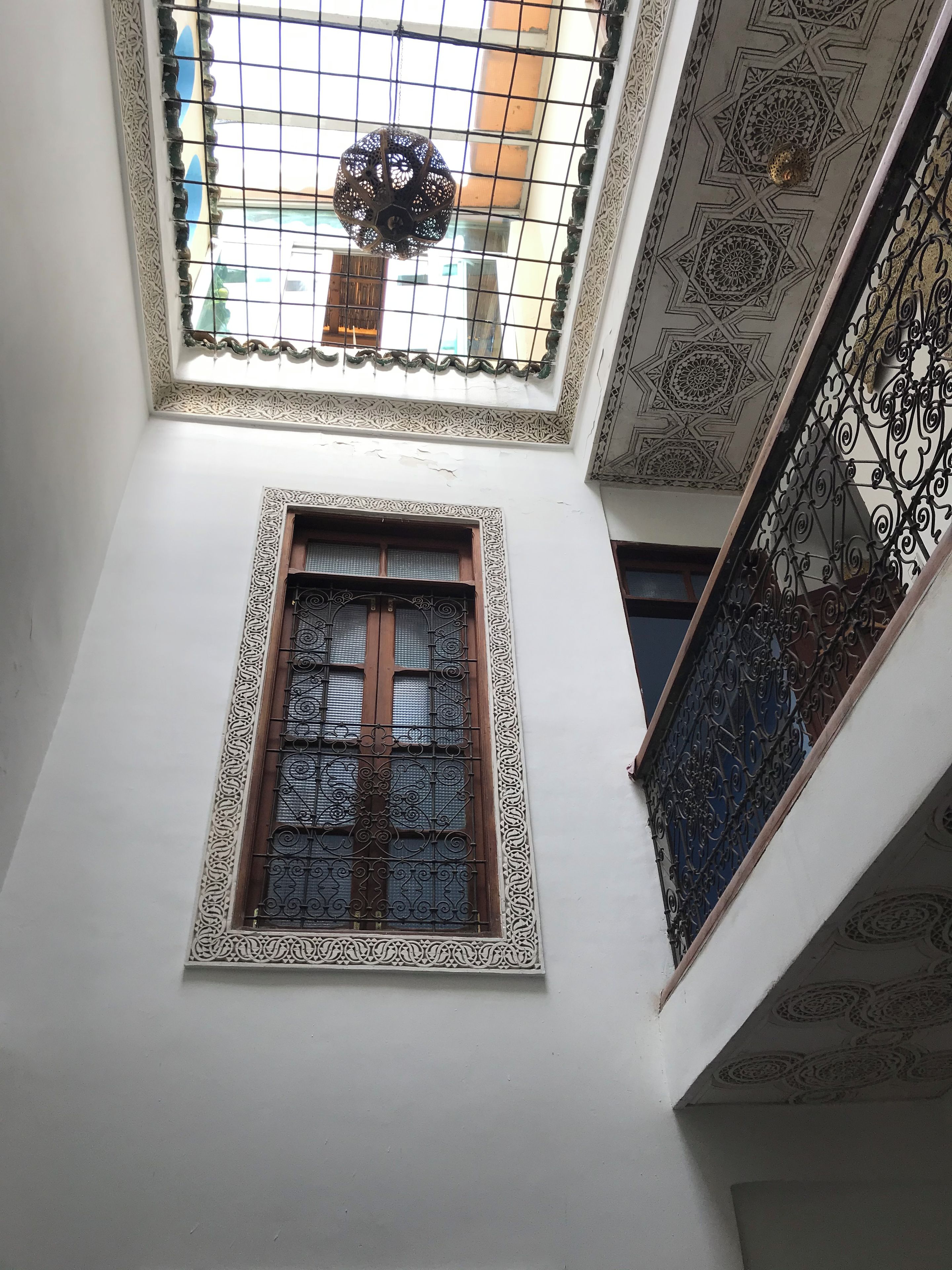 A room with a skylight, a window with ornate metal grilles, and a decorative ceiling.