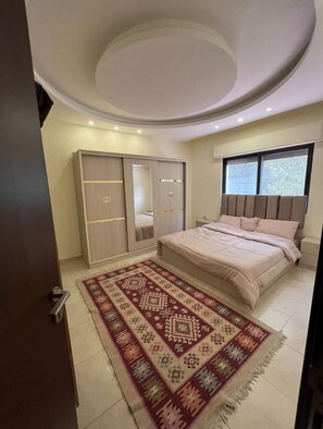 Une chambre à coucher avec un lit, une armoire et un tapis à motifs.