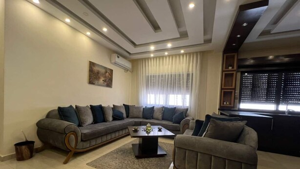 A living room with a sectional sofa, a coffee table, and a small armchair. - Spacious 3BR Amman Stay with Balcony & Free Parking (Amman)