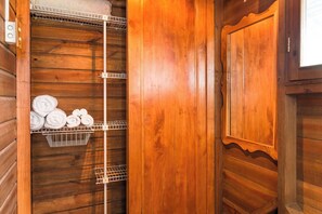 Un interior de madera con un estante metálico que sostiene toallas enrolladas.
