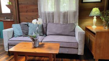 A cozy living room with a sofa, a small wooden table, and a vase with flowers.