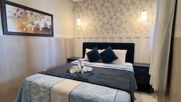 A hotel room with a bed, bedside table, and a wall-mounted air conditioning unit.