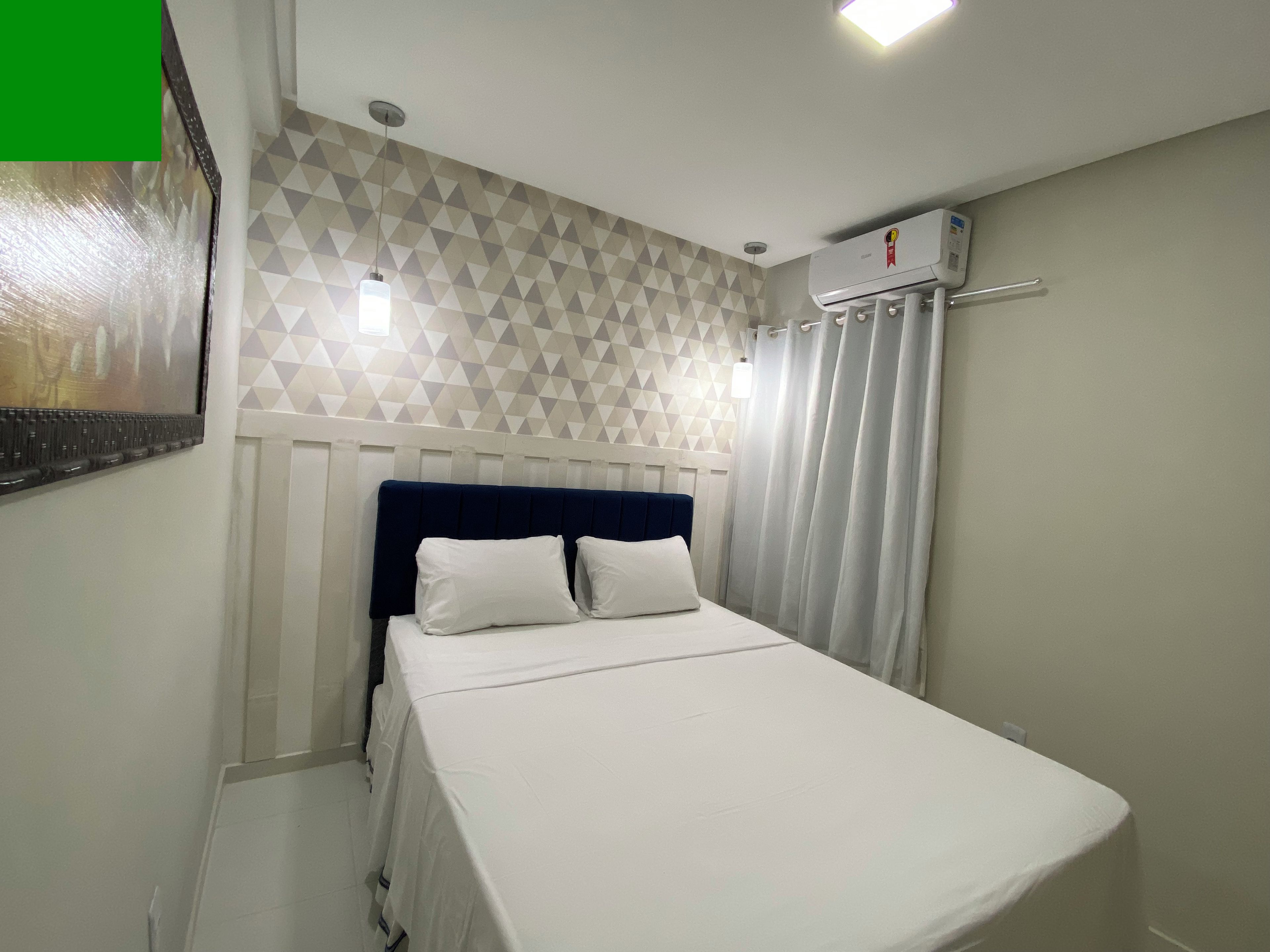 Una camera d'albergo con un letto, un condizionatore d'aria a parete e una parete con motivo geometrico.