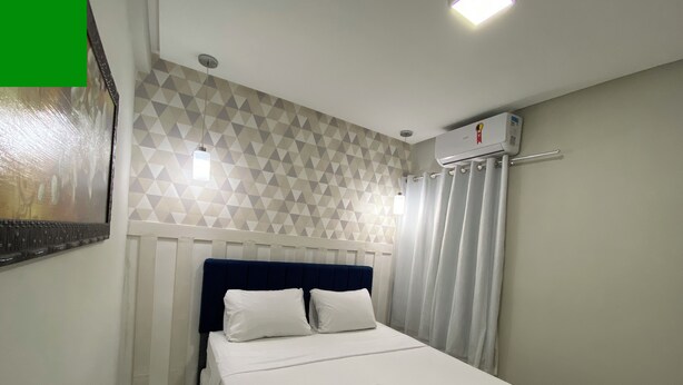 A hotel room with a bed, a wall-mounted air conditioner, and a geometric-patterned wall. - 302 - 2 Quartos Encatador (Belém)