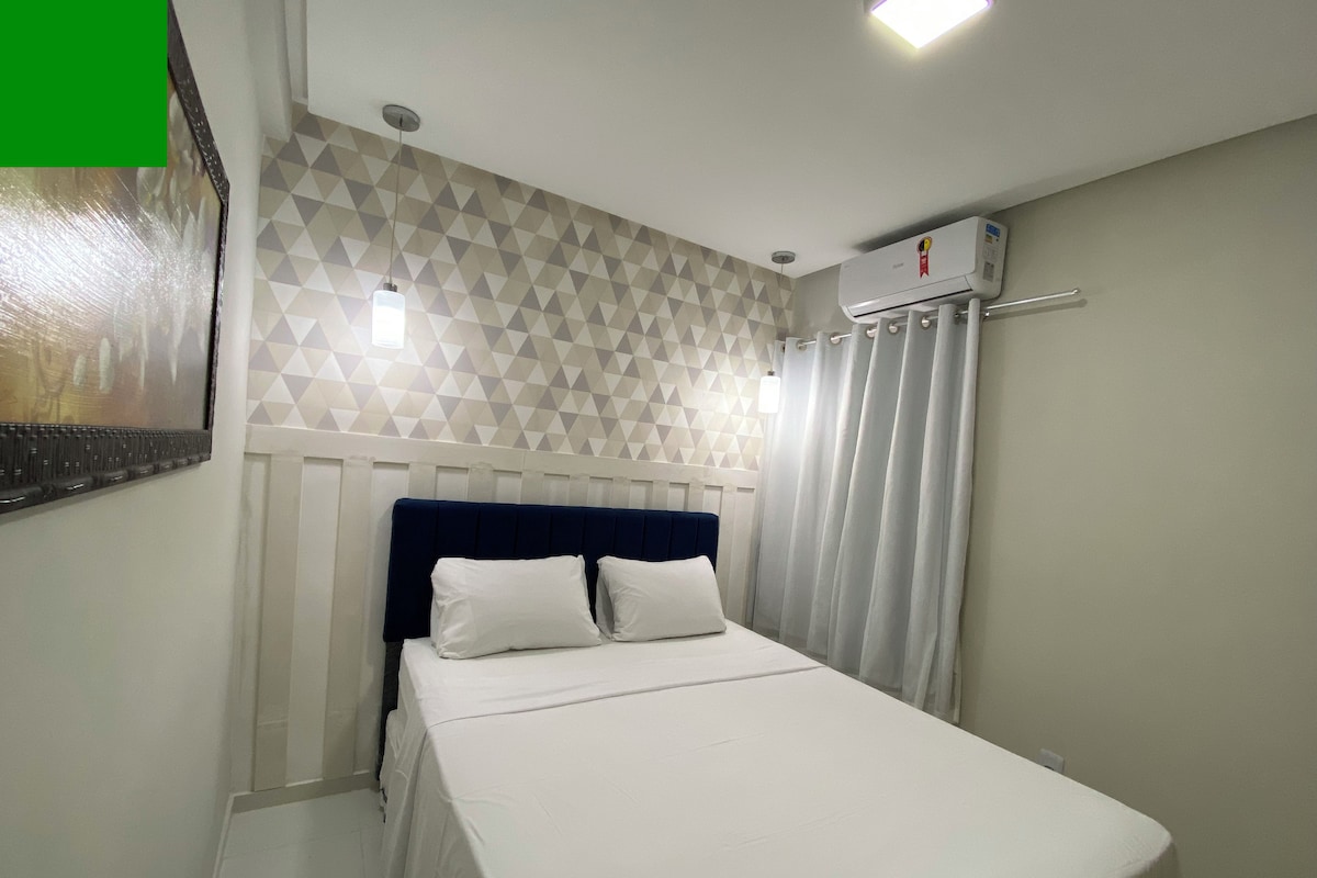 Una habitación de hotel con una cama, aire acondicionado de pared y una pared con estampado geométrico.
