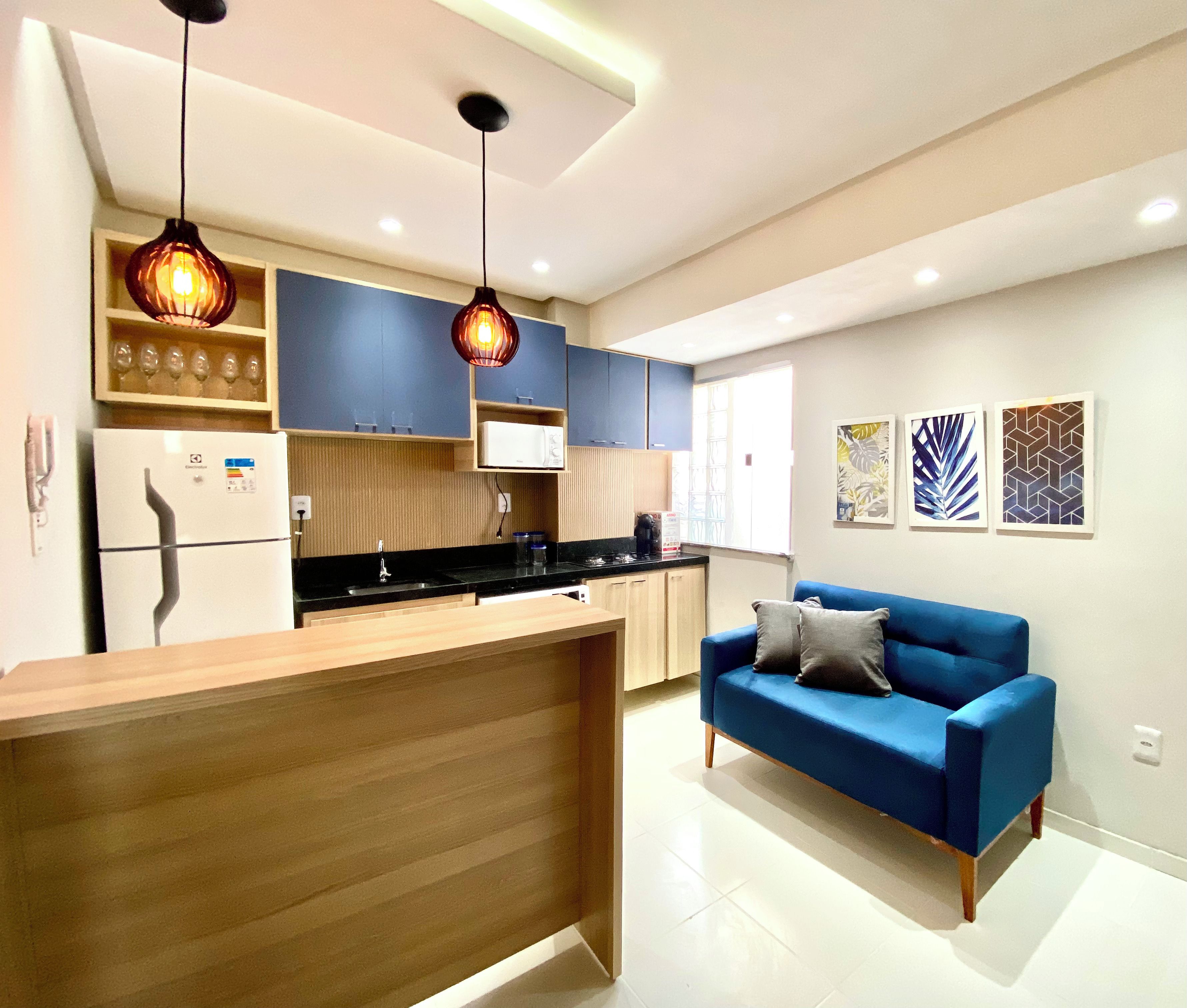 A modern kitchen with a wooden island, blue cabinets, and pendant lighting.