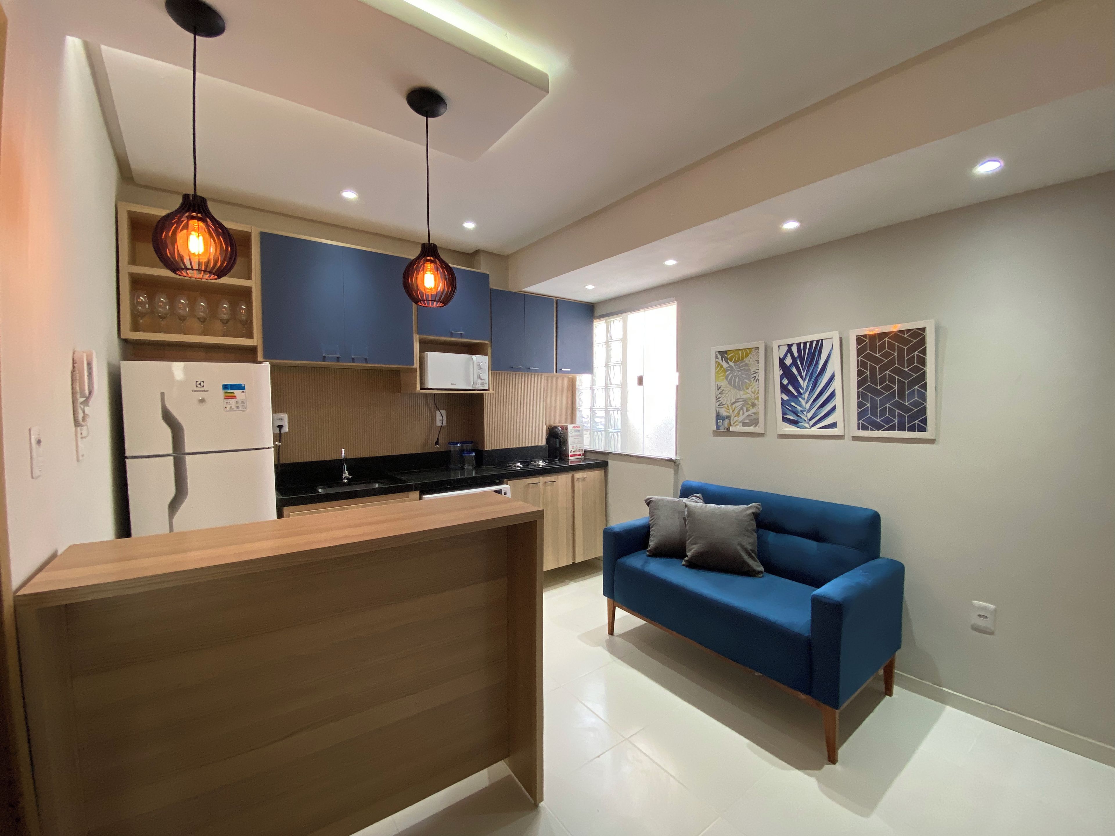 Una cocina moderna con isla de madera, armarios azules e iluminación colgante.