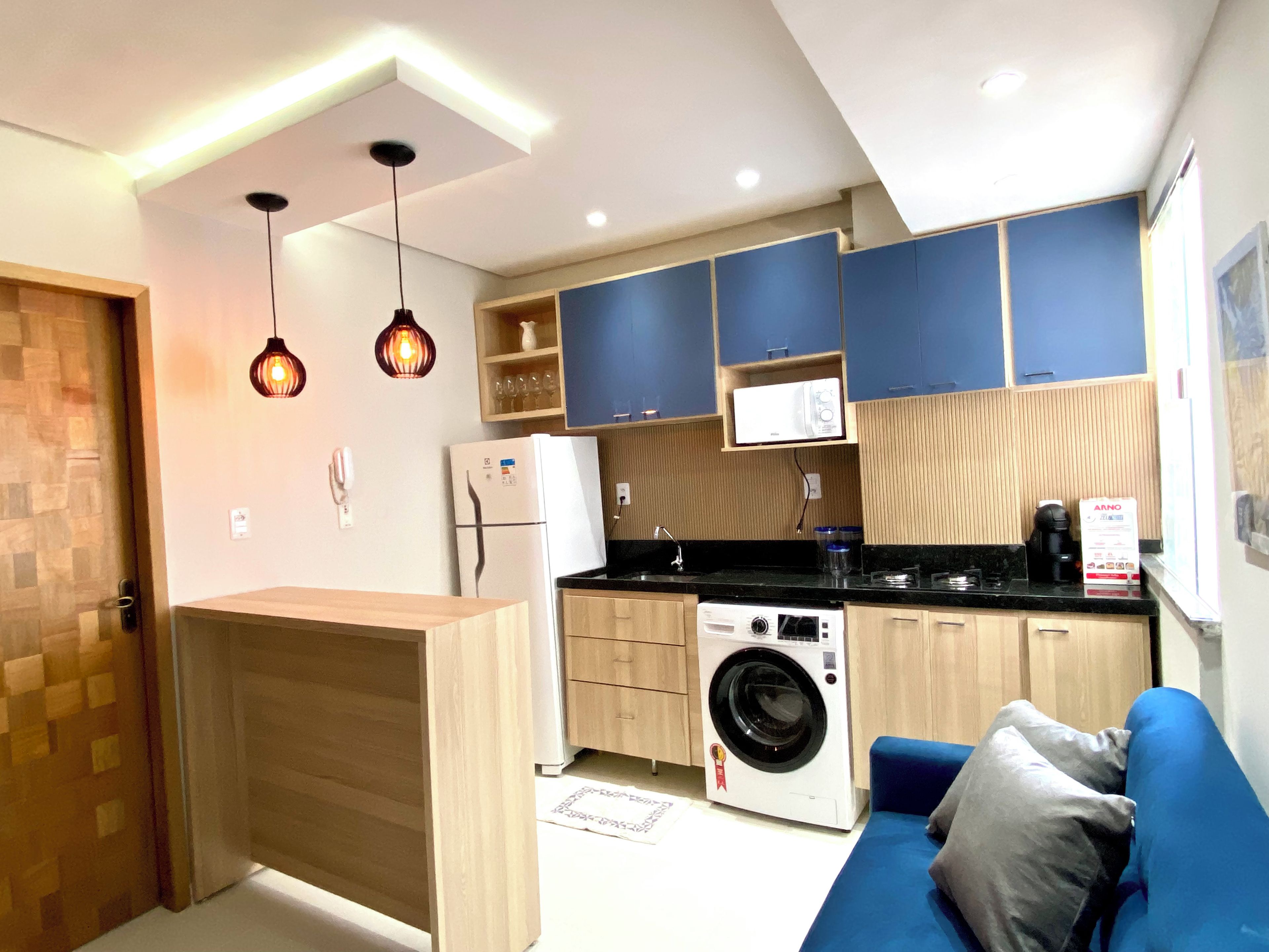 Cocina compacta con lavadora, microondas y cafetera.