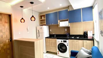 Cocina compacta con lavadora, microondas y cafetera.