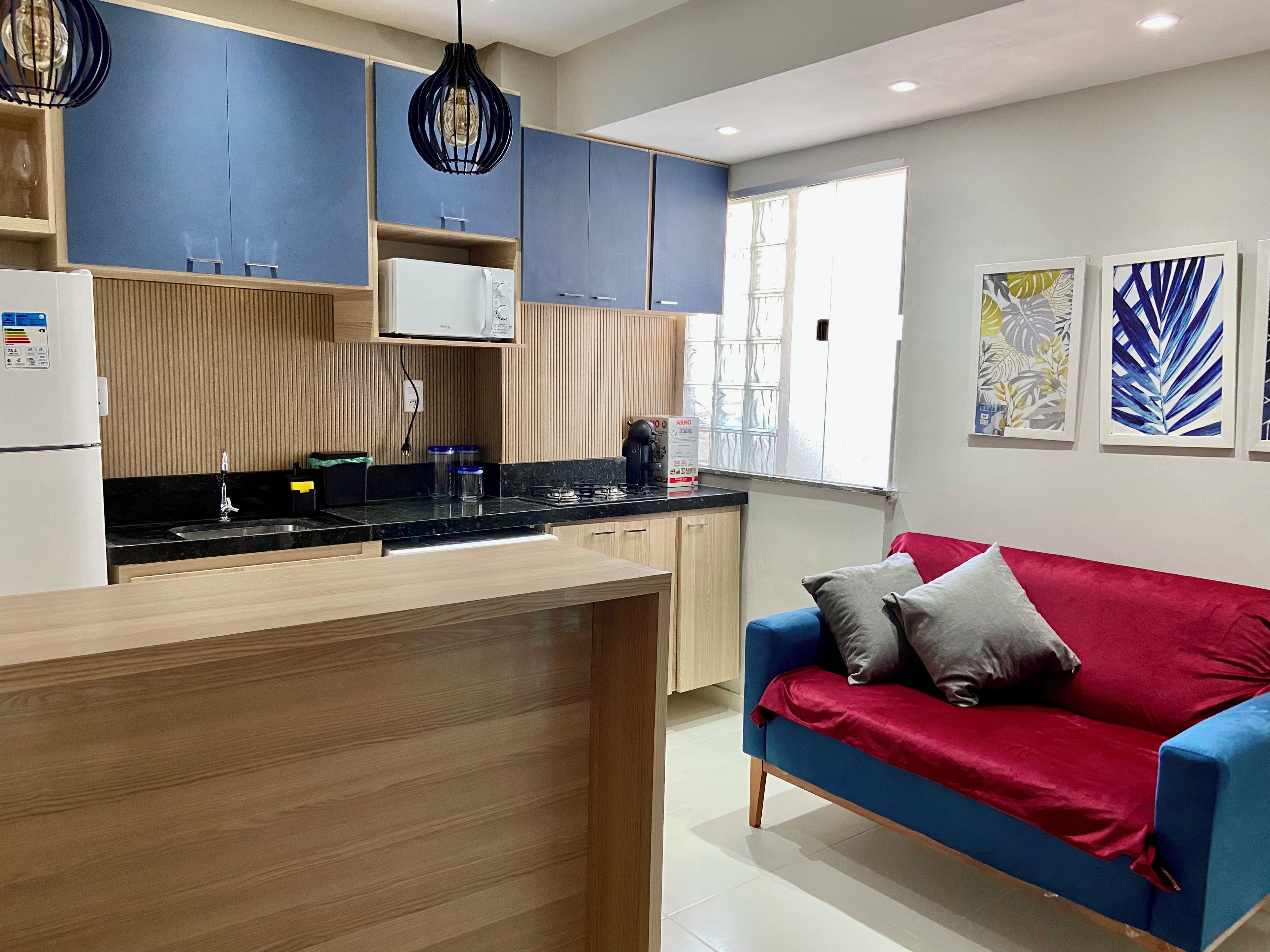 Una cocina moderna con armarios de madera, estufa integrada y un sofá rojo en la sala de estar.
