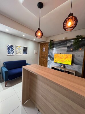 Ein Empfangsbereich mit einem Holzbüro, einem blauen Sofa und einem wandmontierten Flachbildfernseher.