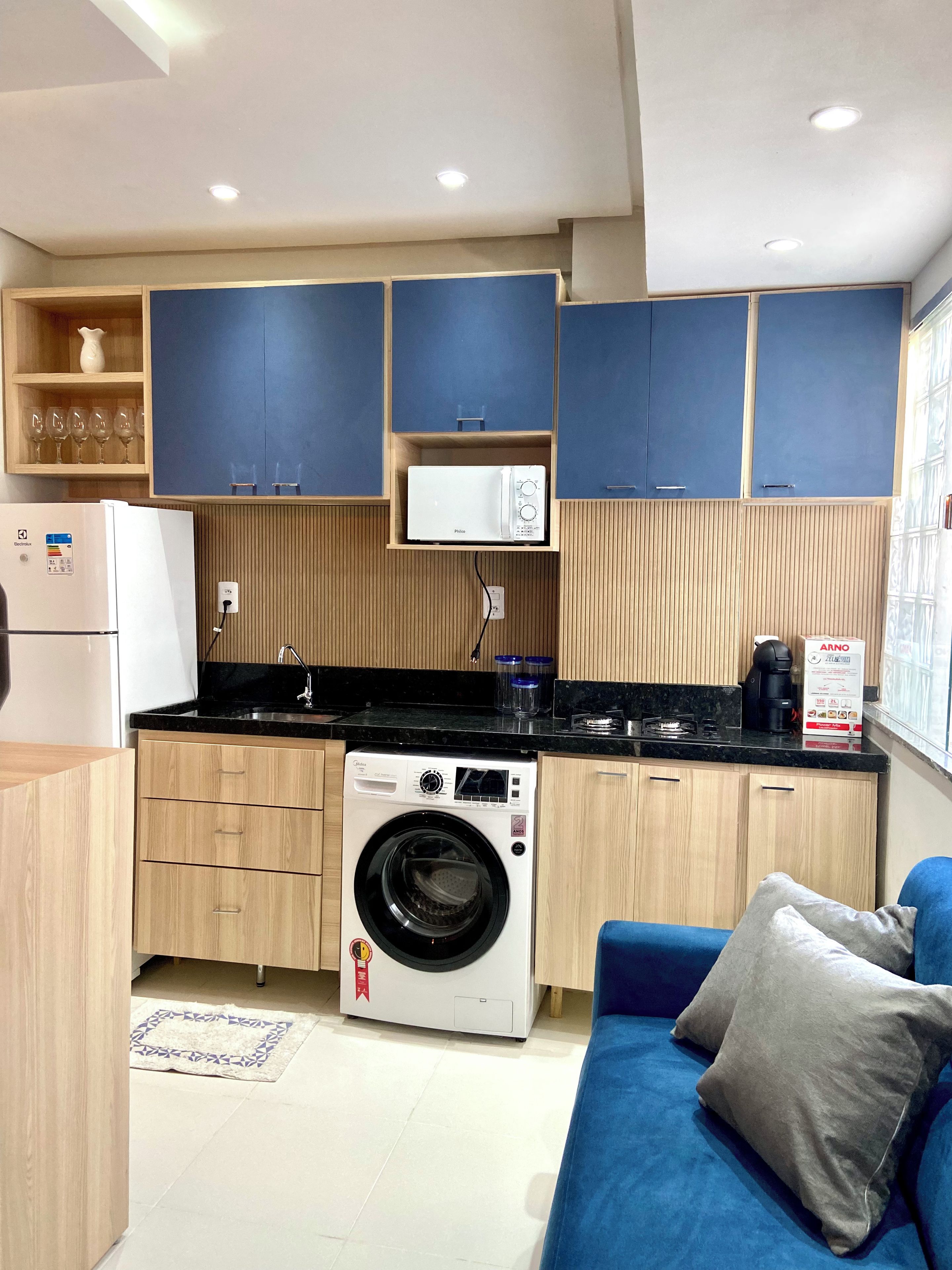 Cocina compacta con lavadora, cafetera y microondas.