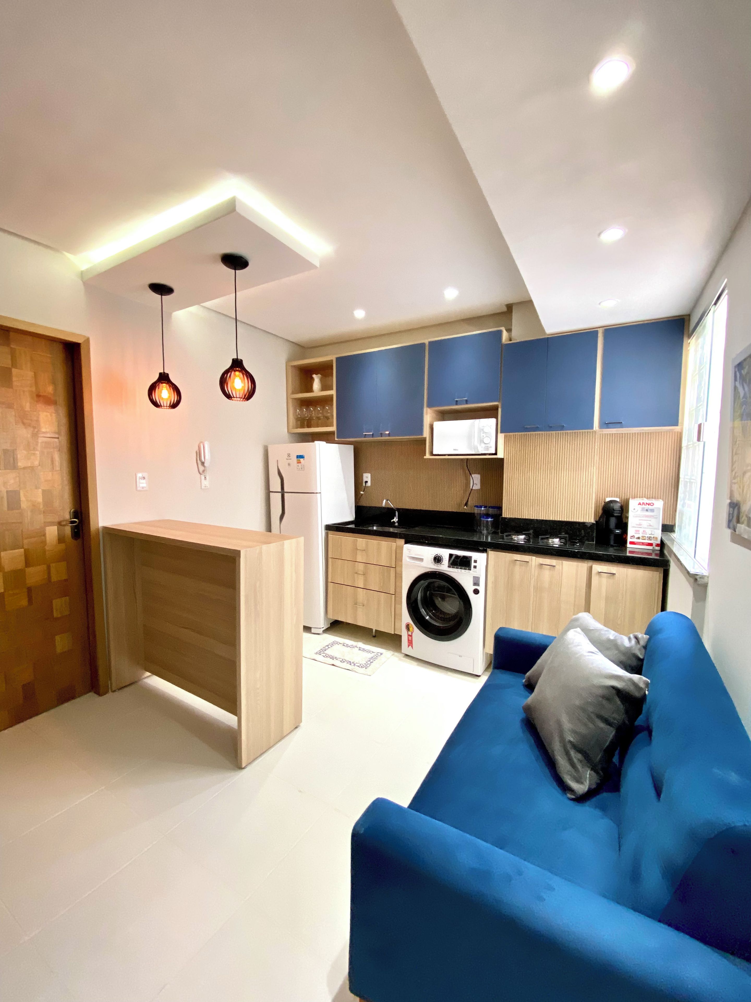 A compact kitchen with a washing machine, a microwave, and a built-in oven.