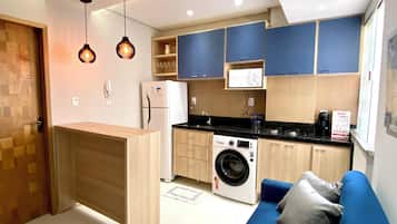 A compact kitchen with a washing machine, a microwave, and a built-in oven.