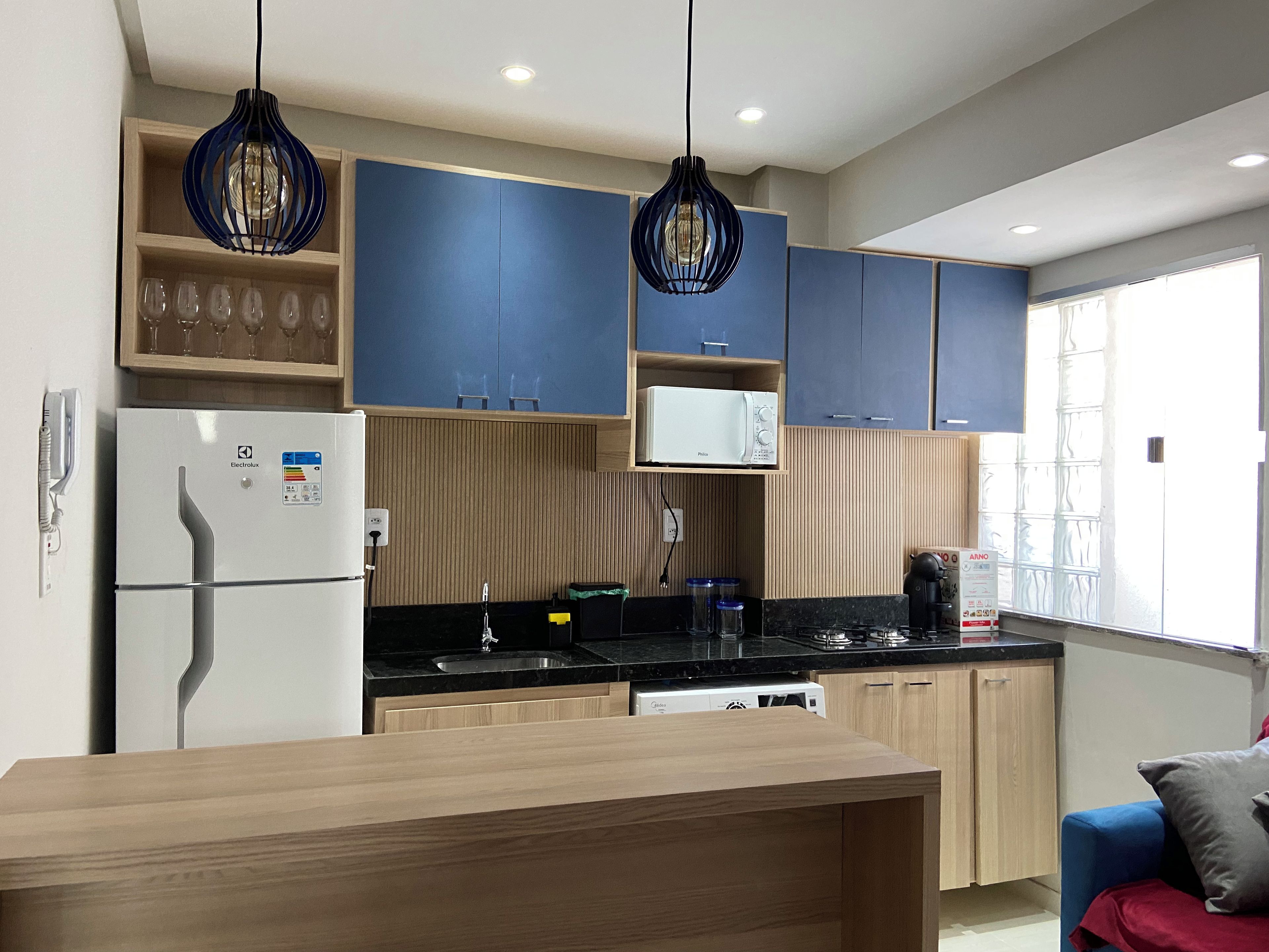 A modern kitchen with wooden cabinets, a built-in microwave, and a stainless steel sink.